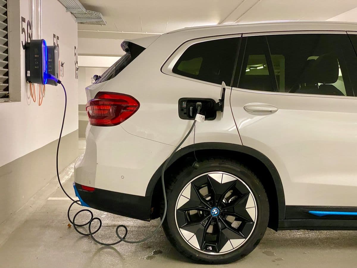 SUV eléctrico blanco conectado a un cargador en un garaje